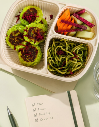 Veg patties, fresh salad and pesto noodles in a three-part tray